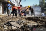 Pekerja memperbaiki jalan di lokasi aspal yang terangkat di Jalan Pasar Kembang, Surabaya, Jawa Timur, Selasa (1/8/2022). Kerusakan jalan yang sempat membuat panik warga sekitar lokasi itu diakibatkan proyek peremajaan pipa air PDAM Surya Sembada Surabaya. ANTARA Jatim/Rizal Hanafi/zk