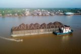 Foto udara kapal cepat melintas di samping kapal tongkang bermuatan batu bara terdampar di muara Sungai Batanghari yang sudah mengalami pendangkalan di Kampung Laut, Tanjung Jabung Timur, Jambi, Selasa (1/8/2023). Pendangkalan yang menghambat lalu lintas angkutan pertambangan itu terjadi akibat pergeseran tanah yang terbawa arus dari bagian hulu, sementara aktivitas pengerukan yang dulunya rutin dilakukan sejak belasan tahun terakhir belum pernah dilakukan. ANTARA FOTO/Wahdi Septiawan/nym.
