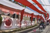Warga melintasi lorong bendera Merah Putih terbentang di Desa Sukamenak, Kabupaten Tasikmalaya, Jawa Barat, Sabtu (12/8/2023). Lorong bendera Merah Putih yang menghiasi jalan perkampungan sepanjang 250 meter itu dibuat warga secara swadaya dalam rangka memeriahkan HUT ke-78 Kemerdekaan RI. ANTARA FOTO/Adeng Bustomi/agr