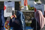 Pengunjung memindai kode Quick Response Code Indonesian Standard (QRIS) pada acara Pekan QRIS Nasional 2023 saat Car Free Day (CFD) di Banda Aceh, Aceh, Minggu (20/8/2023). Pekan QRIS Nasional 2023 tersebut merupakan upaya BI mengkampanyekan penggunaan QRIS sebagai alat pembayaran non tunai di tengah masyarakat dengan target 45 juta pengguna baru dan 1 miliar transaksi QRIS pada tahun 2023 secara nasional. ANTARA/Khalis Surry
