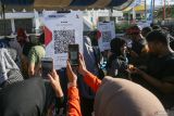 Pengunjung memindai kode Quick Response Code Indonesian Standard (QRIS) pada acara Pekan QRIS Nasional 2023 saat Car Free Day (CFD) di Banda Aceh, Aceh, Minggu (20/8/2023). Pekan QRIS Nasional 2023 tersebut merupakan upaya BI mengkampanyekan penggunaan QRIS sebagai alat pembayaran non tunai di tengah masyarakat dengan target 45 juta pengguna baru dan 1 miliar transaksi QRIS pada tahun 2023 secara nasional. ANTARA/Khalis Surry