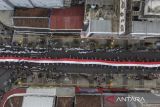 Foto udara peserta membentangkan bendera merah putih saat kirab kebangsaan merah putih di Kota Tasikmalaya, Jawa Barat, Jumat (25/8/2023). Kirab merah putih yang diikuti dari masyarakat, tokoh lintas agama, TNI dan Polri se-Priangan Timur itu, bertujuan untuk menjaga persatuan NKRI dan menumbuhkan nasionalisme dan sikap toleransi antarberagama. ANTARA FOTO/Adeng Bustomi/agr