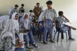 Siswa menunggu antrean pererekaman data identitas KTP elektronik di SMA Negeri 1 Baregbeg, Kabupaten Ciamis, Jawa Barat, Kamis (31/8/2023). Disdukcapil Ciamis melakukan perekaman E-KTP bagi siswa dengan sistem jemput bola di sekolah untuk memfasilitasi hak pilih pada Pemilu 2024, dengan data pemilih pemula usia 17 tahun di Ciamis yang belum memiliki KTP sebanyak 12.133 orang. ANTARA FOTO/Adeng Bustomi/aww.