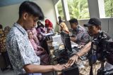 Petugas Dinas Kependudukan dan Pencatatan Sipil (Disdukcapil) merekam data identitas siswa di SMA Negeri 1 Baregbeg, Kabupaten Ciamis, Jawa Barat, Kamis (31/8/2023). Disdukcapil Ciamis melakukan perekaman E-KTP bagi siswa dengan sistem jemput bola di sekolah untuk memfasilitasi hak pilih pada Pemilu 2024, dengan data pemilih pemula usia 17 tahun di Ciamis yang belum memiliki KTP sebanyak 12.133 orang. ANTARA FOTO/Adeng Bustomi/aww. 