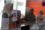 Petugas menyerahkan pencairan tunai Bantuan Sosial (Bansos) kepada anggota keluarga Penerima Manfaat (KPM) di Kantor PT Pos Cabang Banda Aceh, Aceh, Selasa (5/9/2023). Kementerian Sosial melalui  Kantor Pos Cabang di daerah itu  menyalurkan bantuan sosial Program Keluarga Harapan (PKH) untuk  triwulan ke tiga tahun 2023 kepada sebanyak 11.330 Keluarga Penerima Manfaat  (KPM) di provinsi Aceh. ANTARA FOTO/Ampelsa.