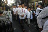 Bacapres Anies Baswedan (tengah) dan Bacawapres Muhaimin Iskandar (ketiga kanan) menyapa warga saat berjalan menuju Makam Sunan Ampel di Surabaya, Jawa Timur, Sabtu (9/9/2023). Kunjungan Anies Baswedan dan Muhaimin Iskandar tersebut dalam rangka berziarah ke Makam Sunan Ampel yang merupakan salah satu penyebar Agama Islam di Pulau Jawa. Antara Jatim/Moch Asim/zk.