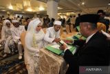 Sepasang pengantin menandatangani buku nikahnya saat Isbat Nikah Massal di Surabaya, Jawa Timur, Selasa (19/9/2023). Pemkot Surabaya bersama Kementerian Agama Surabaya dan Pengadilan Agama Surabaya menggelar kegiatan Isbat Nikah massal yang diikuti 225 pasangan dari berbagai golongan umur dengan tujuan untuk mengesahkan perkawinan pasangan pengantin itu secara hukum yang sebelumnya hanya sah secara agama. ANTARA Jatim/Didik Suhartono/zk 