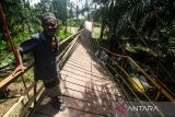 Warga bergantungan di besi saat melewati jembatan gantung yang terputus di Desa Alue Keujruen, Kecamatan Tanah Luas, Aceh Utara, Aceh. Selasa (10/10/2023). Putus dan ambruknya jembatan gantung penghubung enam kecamatan tersebut dikarenakan kondisi rekonstruksi tua sehingga tidak mampu menahan beban berat kendaraan roda empat yang kerap melewati jembatan tersebut. ANTARA/Rahmad