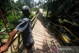 Warga bergantungan di besi saat melewati jembatan gantung yang terputus di Desa Alue Keujruen, Kecamatan Tanah Luas, Aceh Utara, Aceh. Selasa (10/10/2023). Putus dan ambruknya jembatan gantung penghubung enam kecamatan tersebut dikarenakan kondisi rekonstruksi tua sehingga tidak mampu menahan beban berat kendaraan roda empat yang kerap melewati jembatan tersebut. ANTARA/Rahmad