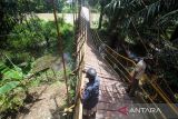 Warga bergantungan di besi saat melewati jembatan gantung yang terputus di Desa Alue Keujruen, Kecamatan Tanah Luas, Aceh Utara, Aceh. Selasa (10/10/2023). Putus dan ambruknya jembatan gantung penghubung enam kecamatan tersebut dikarenakan kondisi rekonstruksi tua sehingga tidak mampu menahan beban berat kendaraan roda empat yang kerap melewati jembatan tersebut. ANTARA/Rahmad