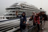 Warga berswafoto dengan latar belakang kapal pesiar Viking Orion yang bersandar di Dermaga Jamrud Utara, Pelabuhan Tanjung Perak, Surabaya, Jawa Timur, Jumat (17/11/2023). Kapal pesiar berbendera Norwegia tersebut memiliki kru kapal sebanyak 464 orang dan membawa wisatawan sebanyak 867 orang dari berbagai negara yang akan mengunjungi sejumlah tempat wisata di Surabaya. Antara Jatim/Didik Suhartono.