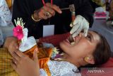 Seorang perempuan Bali mengikuti ritual Metatah atau potong gigi massal yang bertepatan dengan hari suci Tumpek Wayang di Pura Agung Lokanatha, Denpasar, Bali, Sabtu (25/11/2023). Kegiatan yang digelar oleh Parisada Hindu Dharma Indonesia (PHDI) Kota Denpasar tersebut diikuti 204 umat Hindu sebagai upaya menghapus stigma bahwa ritual potong gigi di Bali menelan biaya besar dan cenderung dinilai menjadi beban bagi sebagian masyarakat yang belum paham maknanya. ANTARA FOTO/Nyoman Hendra Wibowo/wsj.