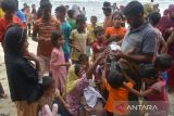 Seorang imigran etnis Rohingya membagikan makanan kepada anak anak Rohingya seusai mendarat  di pantai desa  Ie Meule, kecamatan Suka Jaya, Pulau Sabang, Aceh, Sabtu (2/12/2023).  Sebanyak 139 imigran etnis Rohingya terdiri dari laki laki,  perempuan dewasa dan anak anak menumpang kapal kayu kembali mendarat di Pulau Sabang, sehingga total jumlah imigran di Aceh tercatat  sebanyak 1.223 orang. ANTARA FOTO/Ampelsa.