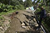 Warga mengamati jalan retak di Tegalkaso, Desa Bencoy, Cireunghas, Kabupaten Sukabumi, Jawa Barat, Rabu (2/12/2023). Badan Penanggulangan Bencana Daerah (BPBD) Kabupaten Sukabumi mencatat akibat pergeseran tanah sedikitnya lima rumah warga rusak, akses jalan penghubung antar kampung retak dan sebanyak 21 warga terpaksa mengungsi di tempat yang aman. ANTARA FOTO/Henry Purba/agr/nz