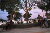 Sejumlah warga duduk santai di bawah lampu hias di Alun-alun Kabupaten Jombang, Jawa Timur, Kamis (14/12/2023). Keberadaan lampu hias di sekitar Alun-alun dan masjid Jami Jombang menjadi daya tarik tersendiri bagi masyarakat untuk menikmati suasana sore hari serta memperindah ruang publik. Antara Jatim/Syaiful Arif.