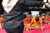 Polisi menghadirkan sejumlah tersangka saat pemusnahan barang bukti narkoba di Polda Jawa Timur, Surabaya, Jawa Timur, Kamis (21/12/2023). Ditresnarkoba Polda Jawa Timur dan jajarannya memusnahkan barang bukti sabu seberat 14,8 kilogram, ganja seberat 3,2 kilogram, pil ekstasi sebanyak 4.308 butir dan pil Double L sebanyak 237.000 butir yang diamankan dari 22 tersangka dalam 13 kasus penyalahgunaan narkoba dalam periode bulan Juli sampai Desember 2023. Antara Jatim/Didik Suhartono.