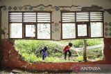 Dua anak bermain di sekitar bangunan yang rusak di SDN Citamiang, Pacet, Kabupaten Cianjur, Jawa Barat, Jumat (22/12/2023). Sejumlah fasilitas sekolah SDN Citamiang seperti tembok, plafon, jendela, dan atap mengalami kerusakan akibat gempa yang mengguncang Kabupaten Cianjur pada 2022 dan hingga kini belum diperbaiki. ANTARA FOTO/Henry Purba/agr