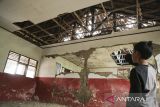 Seorang anak menunjukan plafon rusak di SDN Citamiang, Pacet, Kabupaten Cianjur, Jawa Barat, Jumat (22/12/2023). Sejumlah fasilitas sekolah SDN Citamiang seperti tembok, plafon, jendela, dan atap mengalami kerusakan akibat gempa yang mengguncang Kabupaten Cianjur pada 2022 dan hingga kini belum diperbaiki. ANTARA FOTO/Henry Purba/agr