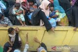 Mahasiswa bersama petugas polisi membantu menaikan sejumlah imigran etnis Rohingya  ke mobil truk saat berlangsung pemindahan paksa di penampungan sementara gedung  Balai Meuseuraya Aceh (BMA), Banda Aceh, Aceh, Rabu (27/12/2023). Sebanyak 137 pengungsi imigran etnis Rohingya terdiri dari laki-laki, perempuan dan anak anak yang ditempatkan di penampungan sementara gedung BMA itu dipindahkan paksa oleh mahasiswa ke kantor Kemenkumham provinsi Aceh. ANTARA FOTO/Ampelsa.