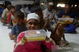 Sejumlah imigran etnis Rohingya bersama anaknya memperoleh  bantuan makanan dari kelompok masyarakat di penampungan sementara gedung  Balai Meuseuraya Aceh (BMA), Banda Aceh, Aceh, Minggu (31/12/2023). Kelompok masyarakat di Aceh menyalurkan bantuan kemanusian  berupa makanan yang berasal dari sumbangan warga kepada sebanyak 137 pengungsi imigran etnis Rohingya terdiri dari laki-laki, perempuan dan anak anak yang masih menempati ruangan parkir  gedung BMA. ANTARA FOTO/Ampelsa