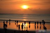 Wisatawan menikmati pemandangan matahari terbenam di kawasan wisata Pantai Kuta, Badung, Bali, Minggu (31/12/2023). Pantai Kuta dipadati oleh ribuan wisatawan dari berbagai negara untuk berlibur pada akhir tahun 2023. ANTARA FOTO/Fikri Yusuf/wsj.