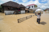 Warga menerobos genangan banjir luapan Sungai Batang Merao yang merendam kawasan permukiman di Koto Dian, Sungai Penuh, Jambi, Sabtu (6/1/2024). Ratusan rumah di sepanjang aliran Batang Merao kota itu yang sempat surut pada Jumat (5/1) kembali terendam banjir hingga setinggi dada orang dewasa pada Sabtu (6/1) dini hari akibat tingginya intensitas hujan di daerah hulu. ANTARA FOTO/Wahdi Septiawan/nz
