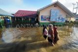 Guru menerobos genangan banjir luapan Sungai Batang Merao yang merendam kompleks SDN 032 di Simpang Tiga Rawang, Sungai Penuh, Jambi, Senin (8/1/2024). Banjir yang terjadi sejak Minggu (31/12/2023) atau memasuki hari ke-9 itu masih menggenangi sekolah, akibatnya sebanyak 109 siswa yang mayoritas rumahnya juga terdampak banjir masih diliburkan, sementara beberapa peralatan elektronik, perangkat ujian siswa dan arsip sekolah rusak. ANTARA FOTO/Wahdi Septiawan/aww.