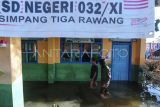 Siswa menerobos genangan banjir luapan Sungai Batang Merao yang merendam SDN 032 di Simpang Tiga Rawang, Sungai Penuh, Jambi, Senin (8/1/2024). Banjir yang terjadi sejak Minggu (31/12/2023) atau memasuki hari ke-9 itu masih menggenangi sekolah, akibatnya sebanyak 109 siswa yang mayoritas rumahnya juga terdampak banjir masih diliburkan, sementara beberapa peralatan elektronik, perangkat ujian siswa dan arsip sekolah rusak. ANTARA FOTO/Wahdi Septiawan/aww.