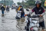 Warga mendorong motornya yang mogok saat melintasi banjir di Kawasan Industri Sapan, Kabupaten Bandung, Jawa Barat, Jumat (12/1/2024). Hujan besar yang mengguyur Bandung Raya pada Kamis (12/1/2024) membuat akses Kawasan Industri Sapan terendam air setinggi 30 hingga 60 sentimeter sehingga berdampak pada aktivitas buruh pabrik di kawasan tersebut. ANTARA FOTO/Raisan Al Farisi/agr