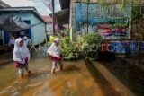 Pelajar menerobos jalan sekolah yang terendam banjir luapan Sungai Batanghari di Tanjung Johor, Pelayangan, Jambi, Senin (22/1/2024). Ribuan rumah dan fasilitas umum di tiga kecamatan yakni Pelayangan, Danau Teluk, dan Danau Sipin Kota Jambi terendam banjir luapan Sungai Batanghari yang terus meninggi dalam dua minggu terakhir, beberapa sekolah telah menetapkan kegiatan belajar mengajar via daring. ANTARA FOTO/Wahdi Septiawan/aww.