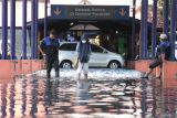 Penumpang menerobos banjir setibanya di kawasan Terminal Purabaya, Bungurasih, Sidoarjo, Selasa (6/2/2024). Banjir yang menggenangi kawasan Terminal Purabaya, Bungurasih sekitar 20-50 sentimeter tersebut diduga karena buruknya drainase seiring dengan tingginya intensitas hujan yang terjadi pada Senin (5/2/2024). Antara Jatim/Moch Asim.