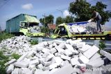 Warga melihat truk yang mengalami kecelakaan di jalan raya Desa Glagahan, Kecamatan Perak, Kabupaten Jombang, Jawa Timur, Selasa (13/2/2024). Kecelakaan yang melibatkan truk nopol L 8262 UN bermuatan bata ringan dan truk boks nopol AD 8017 OC bermuatan paket tersebut mengakibatkan dua orang meninggal dunia di lokasi serta dua orang luka-luka, sementara polisi belum bisa menyimpulkan penyebab kecelakaan. Antara Jatim/Syaiful Arif.