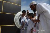 Sejumlah murid taman kanak kanak (TK) bersama orang tua murid dan guru mencium Hajar Aswad tawaf  saat mengikuti praktek manasik haji di Asrama Haji, Banda Aceh, Senin (19/2/2024). Latihan manasik haji diikuti sejumlah murid taman kanak-kanak itu  untuk memperkenalkan tata cara ibadah haji sebagai rukun Islam ke-5 dan edukasi kepada anak sejak usia dini. ANTARA FOTO/Ampelsa.