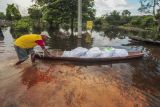 Warga mendorong perahunya melewati jalan yang tergenang banjir luapan Sungai Batanghari di Pematang Jering, Muaro Jambi, Jambi, Senin (26/2/2024). Banjir yang telah terjadi selama hampir dua bulan dan merendam kawasan permukiman dan jalan di daerah itu sempat surut setinggi 60 sentimeter, namun kembali naik dalam tiga hari terakhir seiring masih tingginya intensitas hujan di bagian hulu. ANTARA FOTO/Wahdi Septiawan/nz. 