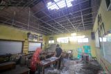 Guru membersihkan ruang kelas SDN Sumput yang rusak di Sumput, Sidoarjo, Jawa Timur, Selasa (27/2/2024). Empat ruang kelas di sekolah itu rusak akibat hujan deras dan angin kencang pada Senin (26/2) sore. Antara Jatim/Umarul Faruq.