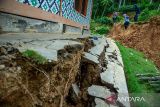 Warga melintas di area terdampak pergerakan tanah di Desa Cibedug, Rongga, Kabupaten Bandung Barat, Jawa Barat, Senin (4/3/2024). Badan Penanggulangan Bencana Daerah (BPBD) Jawa Barat menetapkan status tanggap darurat tanah bergerak di Kampung Cigombong tersebut selama 12 hari ke depan mulai 1 Maret 2024, sebagai antisipasi pergerakan tanah per menit dan timbunan tanah ke Sungai Cidadap. ANTARA FOTO/Novrian Arbi/agr