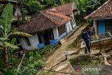 Seorang pewarta foto berada diantara rumah yang rusak dampak pergerakan tanah di Desa Cibedug, Kecamatan Rongga, Kabupaten Bandung Barat, Jawa Barat, Selasa (5/3/2024). Pusat Vulkanologi dan Mitigasi Bencana Geologi (PVMBG) memprediksi pergerakan tanah yang menghancurkan 10 rumah dan 192 kk mengungsi tersebut tidak akan meluas karena sudah terlokalisir dengan batas rekahan tanah yang berbentuk tapal kuda. ANTARA FOTO/Raisan Al Farisi/agr