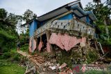 Warga melintas di samping rumah yang rusak dampak pergerakan tanah di Desa Cibedug, Kecamatan Rongga, Kabupaten Bandung Barat, Jawa Barat, Selasa (5/3/2024). Pusat Vulkanologi dan Mitigasi Bencana Geologi (PVMBG) memprediksi pergerakan tanah yang menghancurkan 10 rumah dan 192 kk mengungsi tersebut tidak akan meluas karena sudah terlokalisir dengan batas rekahan tanah yang berbentuk tapal kuda. ANTARA FOTO/Raisan Al Farisi/agr