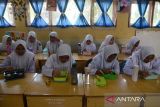 Sejumlah siswa menyantap makanan siang  gratis di SMP Negeri-1 Darul Imarah, kabupaten Aceh Besar, Aceh, Selasa (5/3//2024). Pemerintah kabupaten Aceh Besar  melaksanakan simulasi program makan siang gratis untuk pelajar  dengan lima jenis makanan bergizi dan sehat senilai Rp15 ribu per porsi.  ANTARA FOTO/Ampelsa.