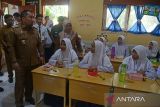 Pj Bupati Aceh Besar, Muhammad Iswanto (kiri) meninjau ruangan kelas saat siswa menyantap makanan siang  gratis di SMP Negeri-1 Darul Imarah, kabupaten Aceh Besar, Aceh, Selasa (5/3//2024). Pemerintah kabupaten Aceh Besar  melaksanakan simulasi program makan siang gratis untuk pelajar  dengan lima jenis makanan bergizi dan sehat senilai Rp15 ribu per porsi.  ANTARA FOTO/Ampelsa.