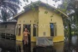 Warga berdiri di depan rumahnya yang terendam banjir di Gedong Karya, Muaro Jambi, Jambi, Selasa (5/3/2024). Banjir luapan Sungai Batanghari yang merendam ratusan rumah di kawasan itu sejak pertengahan Desember tahun lalu masih belum berakhir hingga kini, sementara kegiatan belajar mengajar langsung di sejumlah sekolah masih diliburkan sehingga warga berharap pemerintah bisa mencarikan solusi untuk pendidikan anak-anak mereka. ANTARA FOTO/Wahdi Septiawan/nym.
