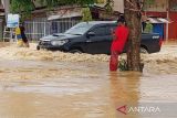 Sebuah mobil melintasi banjir setinggi lutut di Kota Sorong