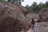 Warga berjalan di samping batu yang terbawa longsor di Langgai, Gantiang Mudiak Utara Surantiah, Kecamatan Sutera, Pesisir Selatan, Sumatera Barat, Selasa (12/3/2024). Akses menuju lokasi bencana tersebut putus dan warga yang terdampak mengharapkan bantuan berupa kebutuhan untuk ibu dan anak serta perbaikan jaringan listrik yang terputus ke desa mereka. ANTARA FOTO/Givo Alputra/Lmo/aww.