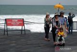 Wisatawan berjalan di dekat papan larangan di objek wisata Tanah Lot, Tabanan, Bali, Kamis (14/3/2024). Badan Meteorologi, Klimatologi, dan Geofisika (BMKG) Wilayah III Denpasar memprediksi terjadinya cuaca ekstrem di wilayah Bali selama tiga hari pada 14-16 Maret 2024 yang merupakan dampak dari terbentuknya bibit siklon tropis 91S dan 94S di wilayah Indonesia. ANTARA FOTO/Nyoman Hendra Wibowo/wsj.