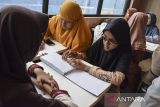 Penyandang disabilitas tunanetra membaca Al Quran Braille saat kegiatan tadarus di Tasikmalaya, Jawa Barat, Minggu (17/3/2024). Yayasan Majelis Taklim Tuna Netra Al-Hikmah menggelar tadarus Al Quran Braille kepada penyandang disabilitas  tunanetra di tempat makan siap saji dalam mengisi waktu menunggu berbuka puasa atau ngabuburit. ANTARA FOTO/Adeng Bustomi/agr