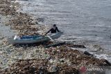 Nelayan menarik perahunya melewati tumpukan sampah plastik di kawasan Pantai Kedonganan, Badung, Bali, Rabu (20/3/2024). Pantai Kedonganan dipadati oleh sampah plastik kiriman yang terdampar terbawa arus laut yang mengganggu aktivitas warga dan nelayan setempat. ANTARA FOTO/Fikri Yusuf/wsj.