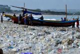 Nelayan mendorong perahunya melewati tumpukan sampah plastik di kawasan Pantai Kedonganan, Badung, Bali, Rabu (20/3/2024). Pantai Kedonganan dipadati sampah plastik kiriman yang terdampar terbawa arus laut yang mengganggu aktivitas warga dan nelayan setempat. ANTARA FOTO/Fikri Yusuf/wsj.
