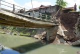 Jembatan ambrol tergerus banjir. Warga terpaksa menyeberangi sungai tak jauh dari jembatan yang ambrol tergerus banjir di Desa Kalidawir, Tulungagung, Jawa Timur, Minggu (24/3/2024). Pondasi di kedua sisi/ujung jembatan penghubung desa itu amblas tergerus luapan air yang membanjiri daerah itu sehingga menyebabkan badan jembatan patah dan turun sekitar 50 centimeter sehingga tidak bisa dilalui  kendaraan. ANTARA Jatim/Destyan Sujarwoko/rf