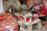 Perajin melakukan pewarnaan pada karya seni barongan atau topeng kepala naga buatannya di rumah produksi barongan Desa Jatimulyo, Tulungagung, Jawa Timur, Salasa (26/3/2024). Topeng kepala naga atau dalam bahasa Jawa disebut dengan istilah barongan itu dijual di kisaran Rp4 juta hingga Rp6 juta, bergantung jenis bahan, ukuran dan tingkat kerumitan ukiran wajah serta pernik hiasan yang melekat pada bagian kepala barong. ANTARA Jatim/Destyan Sujarwoko