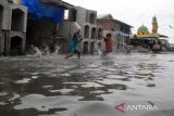 Sejumlah warga melintasi genangan air saat banjir rob di Medan Belawan, Sumatera Utara, Rabu (29/3/2024). Badan Meteorologi Klimatologi dan Geofisika (BMKG) Stasiun Meteorologi Klas II Maritim Belawan memperkirakan banjir rob yang melanda daerah tersebut akan berlangsung hingga 30 Maret 2024 dan meminta masyarakat agar waspada dengan tinggi air yang mencapai 2,6 meter. ANTARA FOTO/Yudi Manar